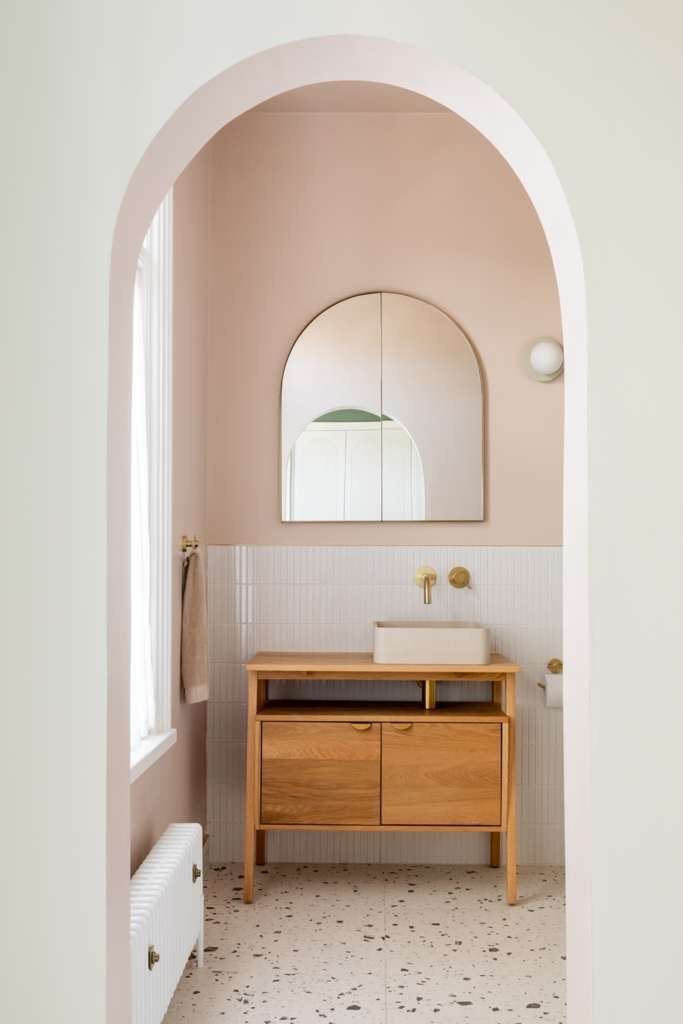 Plastered archway framing a blush pink bathroom