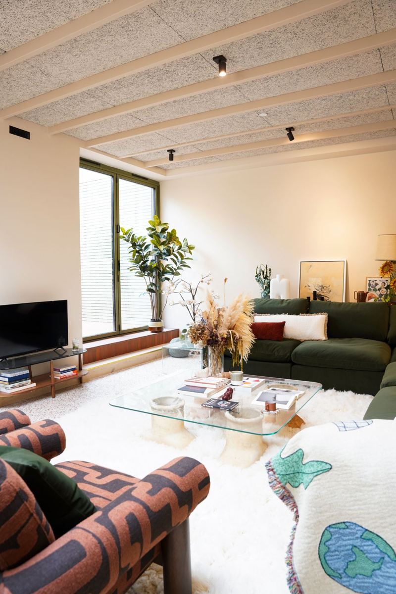 Open-plan living room with warm white walls, beamed ceiling and green sofa
