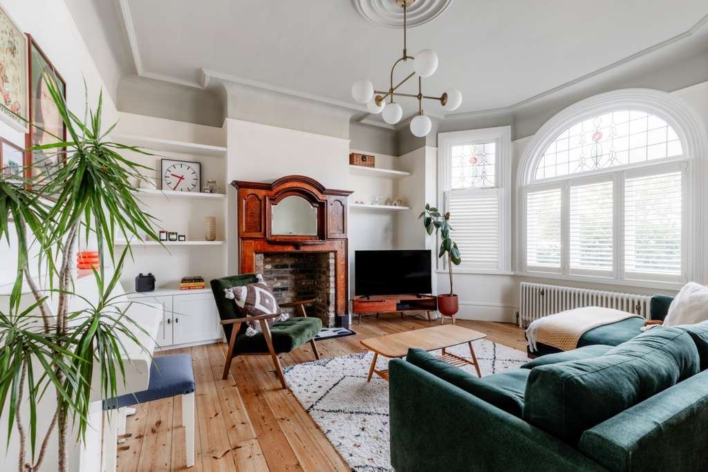 Period living room with white walls, fireplace and arched bay window